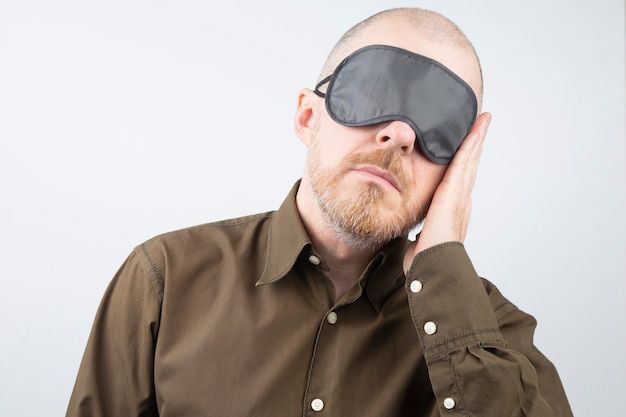 Foto hombre barbudo con los ojos vendados para dormir