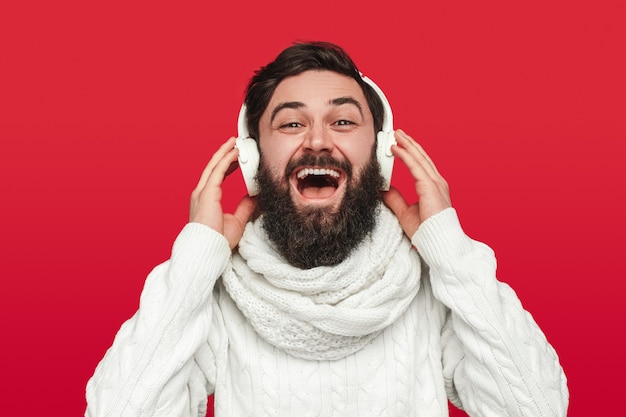 Hombre barbudo optimista escuchando música durante la celebración de Navidad