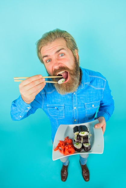 Hombre barbudo con plato de sushiroll plato de jengibre en escabeche de maki rolls susi hombre de nutrición exótica