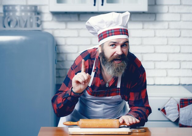 Hombre barbudo presente plato Cocinero profesional Chef en delantal de cocinero