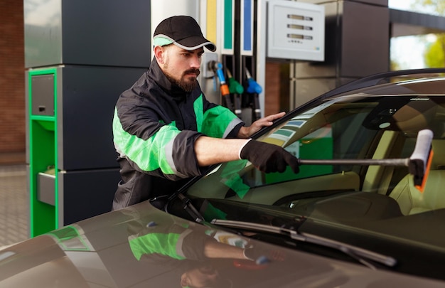 Hombre barbudo que lava el parabrisas del coche moderno