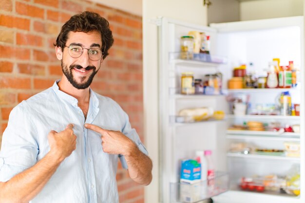 Hombre barbudo que se siente feliz, sorprendido y orgulloso, señalando a sí mismo con una mirada emocionada y asombrada