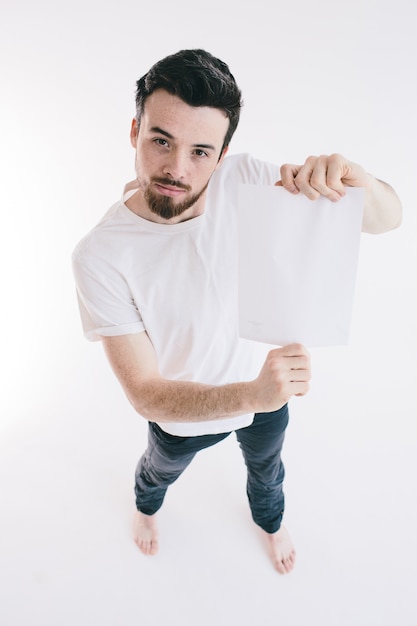 Foto hombre barbudo que sostiene una hoja de papel blanco en blanco