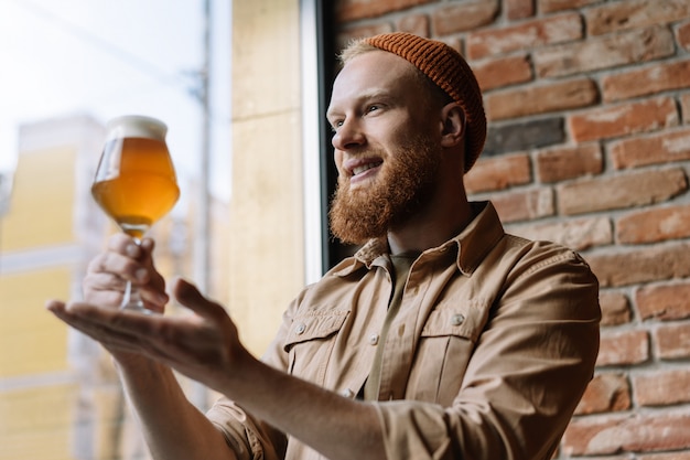 Hombre barbudo que sostiene un vaso con cerveza