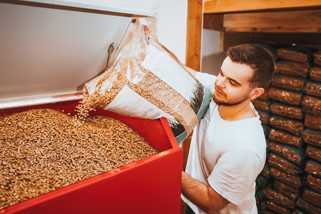 Foto un hombre barbudo que usa pellets de madera como una fuente de combustible renovable y ecológica para su caldera que calienta su casa en invierno