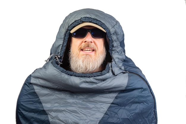 hombre barbudo en un saco de dormir en un fondo blanco equipo para la recreación en el turismo y los viajes