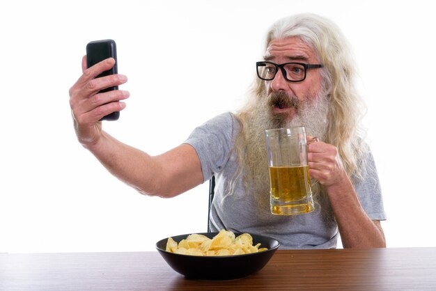 Hombre barbudo senior feliz sonriendo mientras toma foto selfie