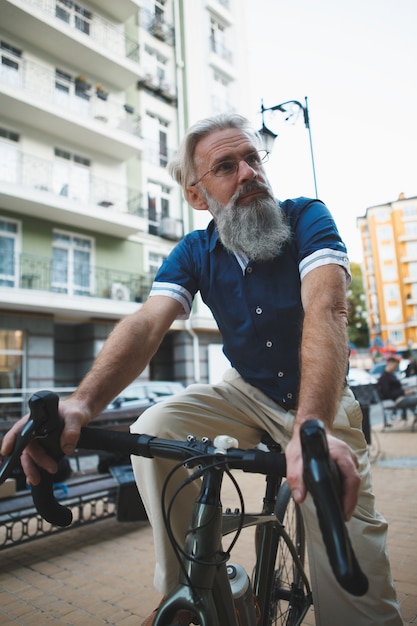 Hombre barbudo senior montando bicicleta en las calles de la ciudad