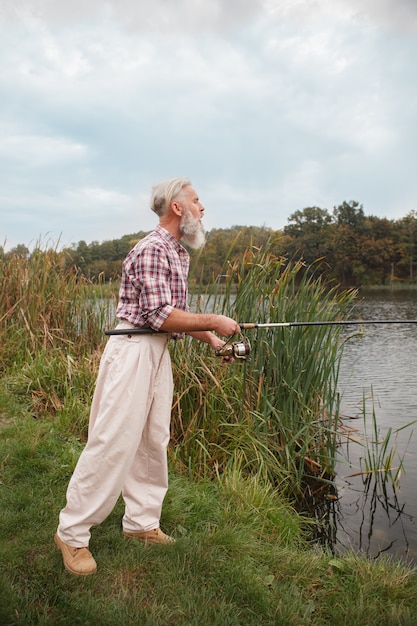 Hombre barbudo senior pescando en un lago