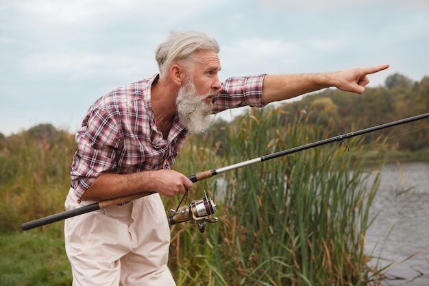 Hombre barbudo senior pescando en un lago