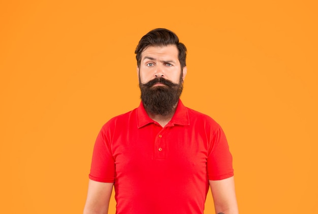 Hombre barbudo serio con bigote en camiseta en cara de fondo amarillo