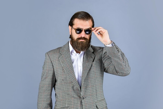 Hombre barbudo serio hombre guapo y exitoso en traje caro Él está en camisa blanca y gafas elegante hombre exitoso en traje posando hombre de negocios usar traje estilo de vida de oficina oficial