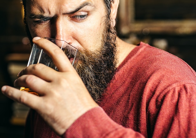 Hombre barbudo serio prueba bebida alcohólica.