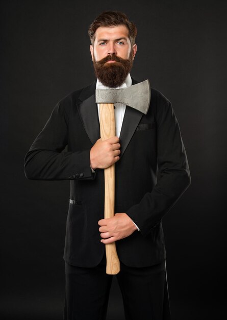 Hombre barbudo serio en traje con fondo oscuro de hacha.