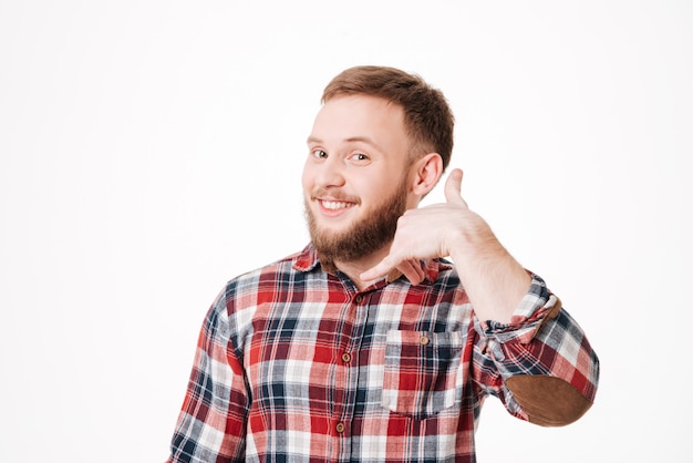 Hombre barbudo sonriente en camisa mostrando señal de teléfono