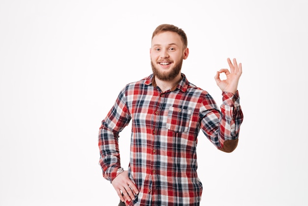Hombre barbudo sonriente en camisa mostrando signo ok