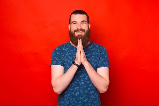 El hombre barbudo sonriente está juntando las manos como en una oración.