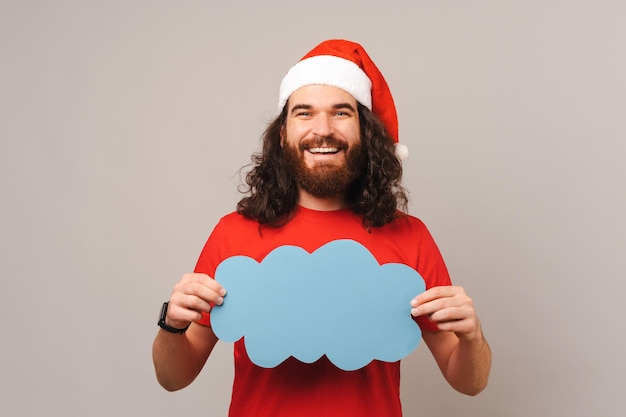 El hombre barbudo sonriente está sosteniendo un discurso de burbuja de nube azul en vacaciones