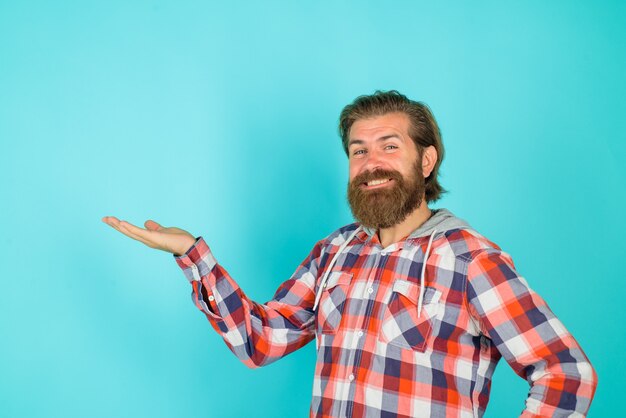 Hombre barbudo sonriente muestra algo espacio de copia de contenido publicitario para su atención de mirada de texto