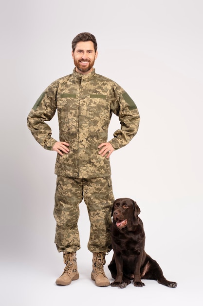 Hombre barbudo sonriente soldado entrenando perro Labrador marrón aislado en fondo blanco