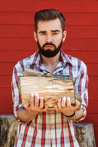 Hombre barbudo sostiene leñas