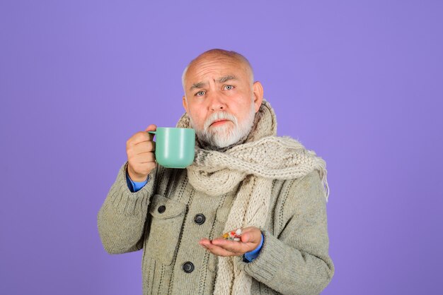 Hombre barbudo tiene píldoras en la mano y taza con medicina de agua y concepto de salud saludable