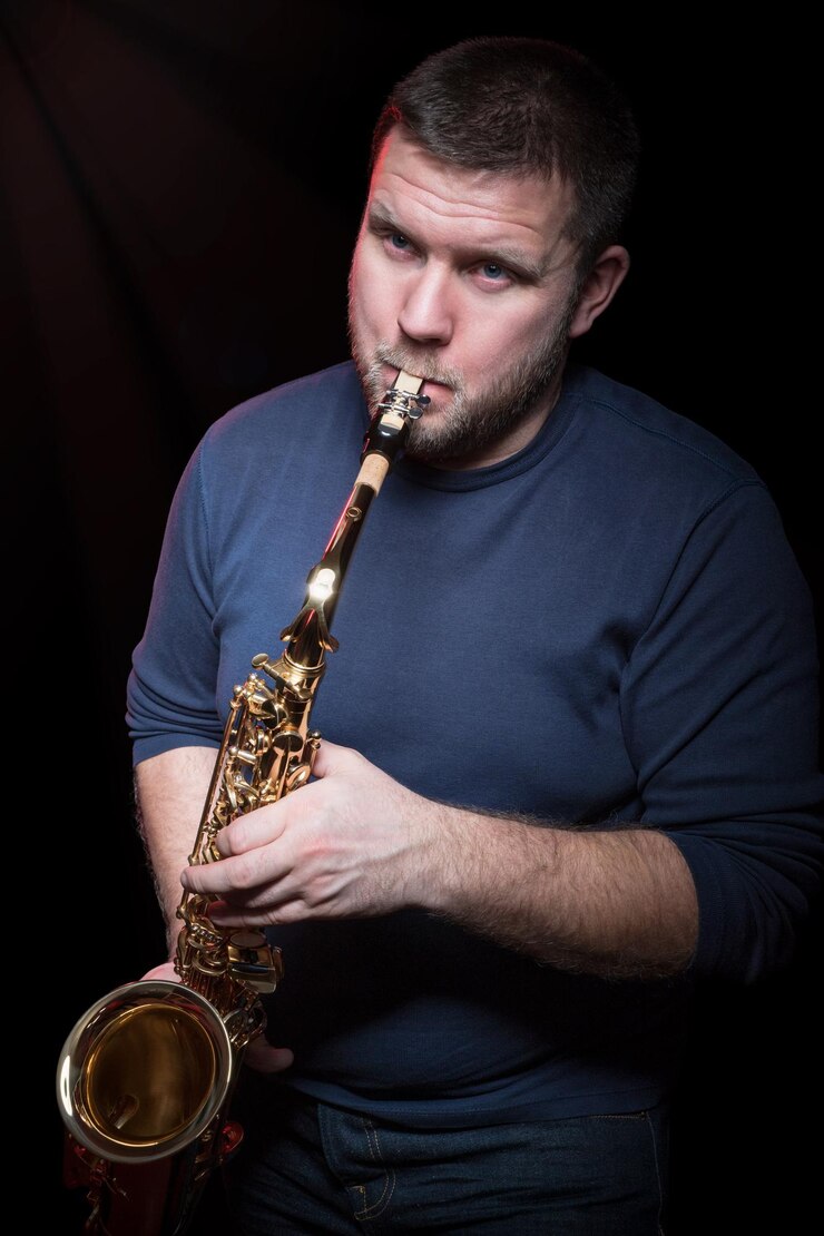 Foto el hombre barbudo toca el primer plano del saxofón, aislado en un fondo negro