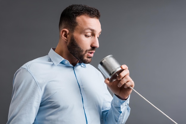 Foto hombre barbudo tomando mientras sostiene lata aislada en gris