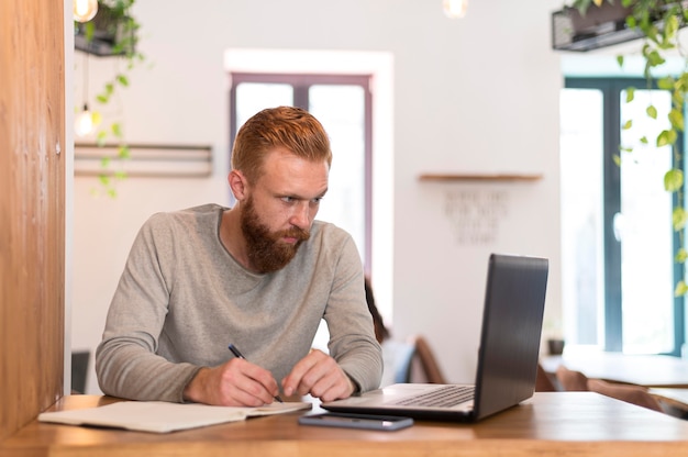 Hombre barbudo tomando notas en el trabajo