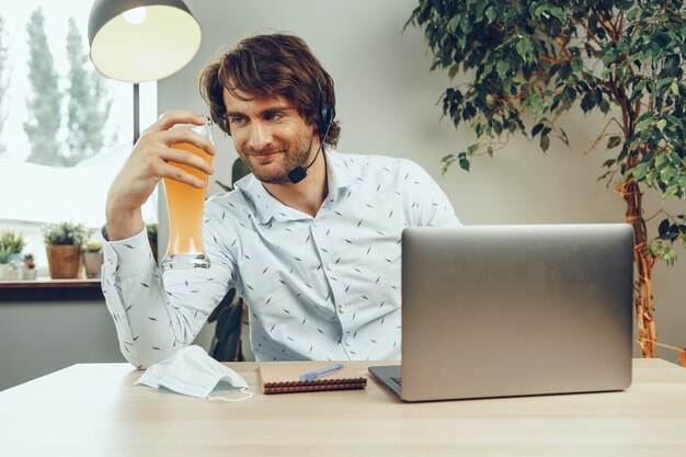 Hombre barbudo usando su computadora portátil mientras bebe un vaso de cerveza