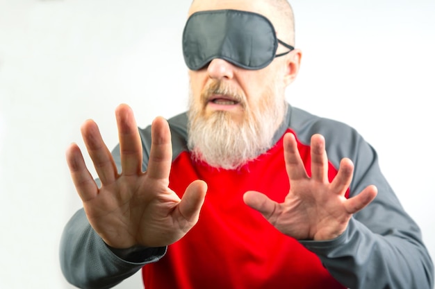 Foto hombre barbudo con una venda para dormir concepto de un ciego buscando en la oscuridad