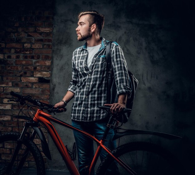 Un hombre barbudo vestido con una camisa de lana tiene una bicicleta de montaña roja.