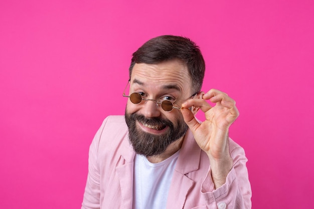 Hombre barbudo vestido con una chaqueta rosa con gafas Retrato de estudio emocional