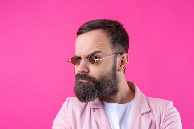 Hombre barbudo vestido con una chaqueta rosa con gafas Retrato de estudio emocional