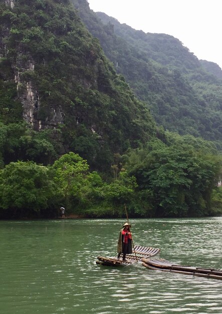 Foto hombre en barco en el río contra las montañas