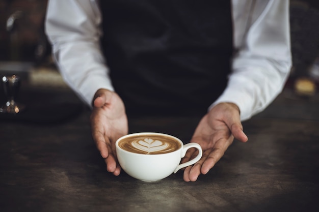 Hombre Barista preparando café para el cliente en la cafetería. Dueño del café que sirve a un cliente en la cafetería.