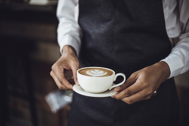 Hombre Barista preparando café para el cliente en la cafetería. Dueño del café que sirve a un cliente en la cafetería.