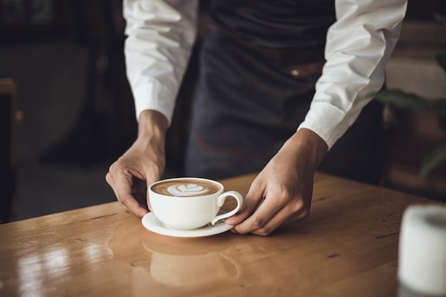 Hombre Barista preparando café para el cliente en la cafetería. Dueño del café que sirve a un cliente en la cafetería.