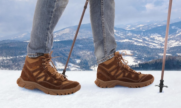 Hombre con bastones de trekking en primer plano de montañas nevadas