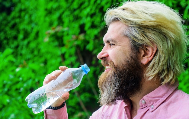 Hombre bebe agua al aire libre. Hombre barbudo con botella de agua. Estilo de vida saludable. Agua potable.