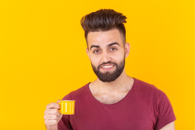 El hombre bebe café de una taza pequeña en la pared amarilla