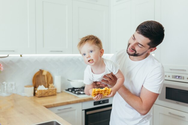 Un hombre con un bebé prepara el desayuno, un padre y un hijo.