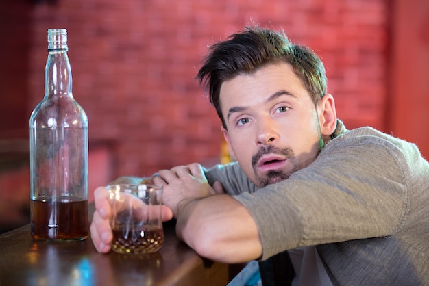 Hombre bebido joven que bebe alcohol en la barra.