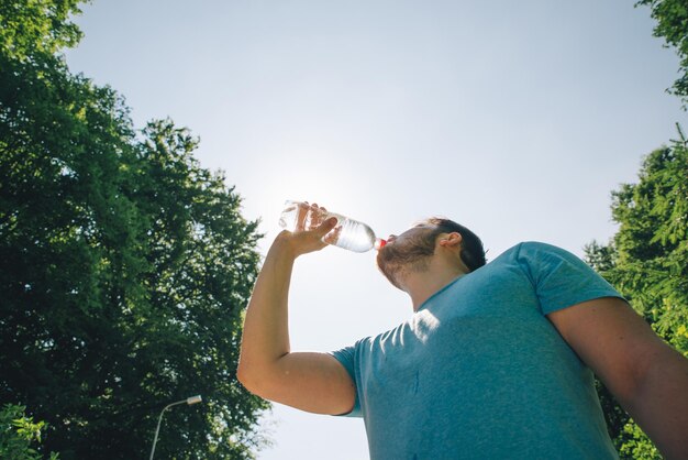 Hombre bebiendo agua en el caluroso día de verano copia espacio