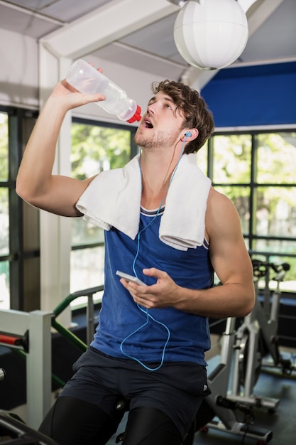 Hombre bebiendo agua y escuchando música en clase de spinning