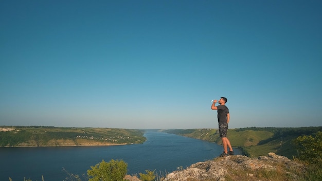 El hombre bebiendo agua en un hermoso río de fondo