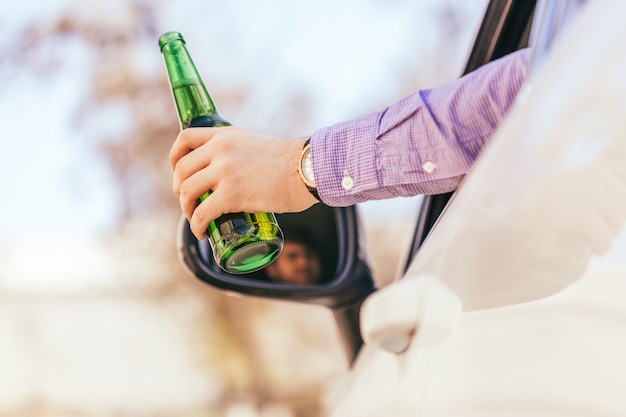 Hombre bebiendo alcohol mientras conduce el auto