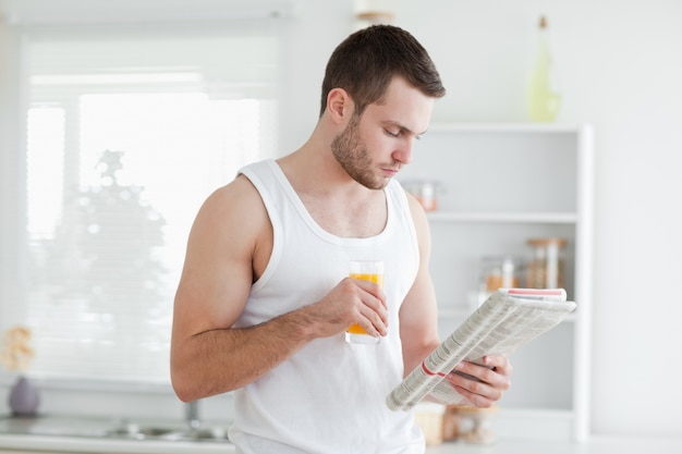 Hombre bebiendo jugo de naranja mientras leía las noticias