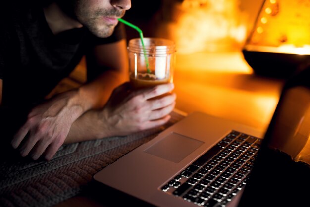 Hombre bebiendo jugo de naranja de un vaso grande mientras ve la película