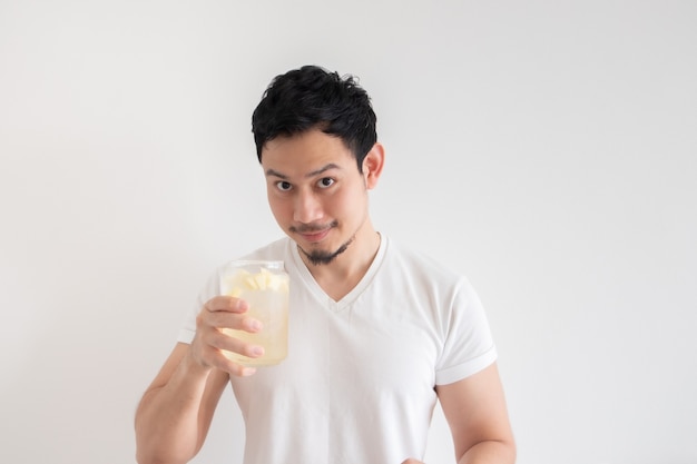 El hombre está bebiendo refresco de limón helado en aislar la pared blanca